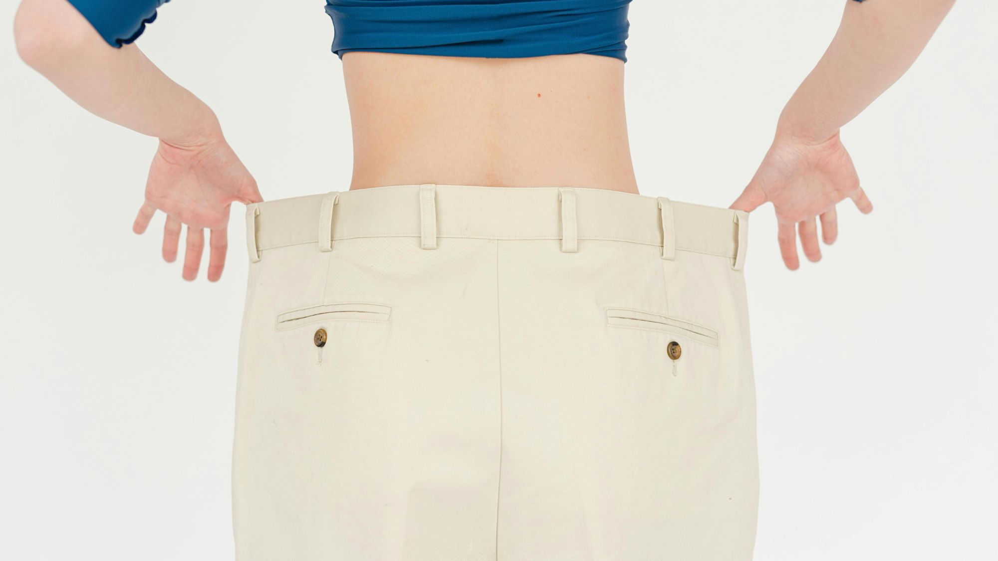 A woman showing a visible gap in her waistband, showing loose stomach skin after her weight loss journey